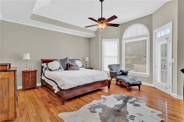 bedroom with light wood-style floors, baseboards, a ceiling fan, and access to exterior