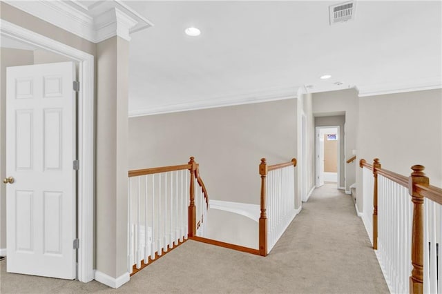 hallway with crown molding, visible vents, carpet, and an upstairs landing