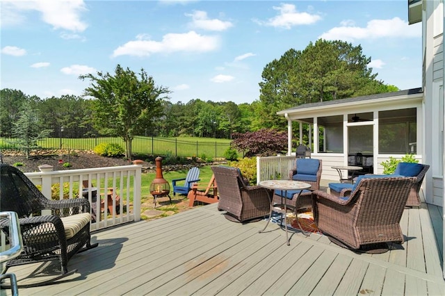 wooden deck featuring a forest view, a fenced backyard, and a sunroom