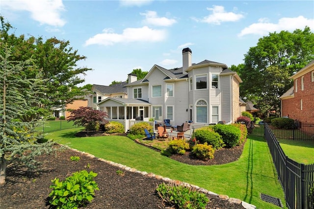rear view of property with a lawn, a patio, a chimney, and a fenced backyard