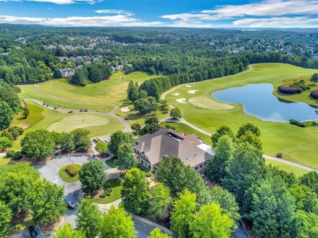 drone / aerial view featuring a water view, golf course view, and a wooded view
