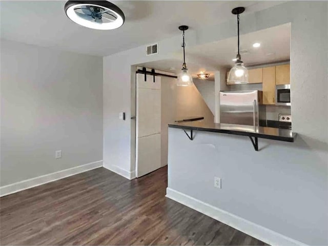 kitchen featuring a barn door, dark hardwood / wood-style floors, decorative light fixtures, a breakfast bar area, and appliances with stainless steel finishes