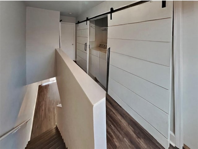 staircase featuring a barn door, hardwood / wood-style floors, and washer and dryer