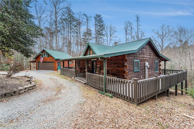 view of side of property with a porch, metal roof, driveway, and a garage