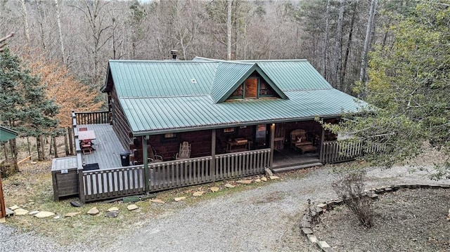 chalet / cabin with a porch, metal roof, and a wooded view