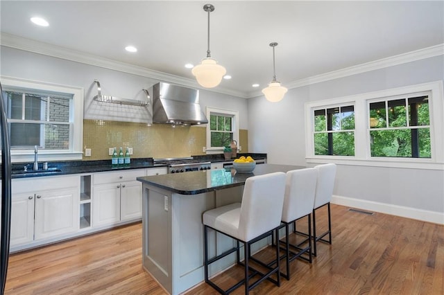 1066 High Point Dr, Atlanta, GA 30306 - kitchen featuring wall chimney exhaust hood, decorative backsplash, a breakfast bar area, stove, and white cabinetry