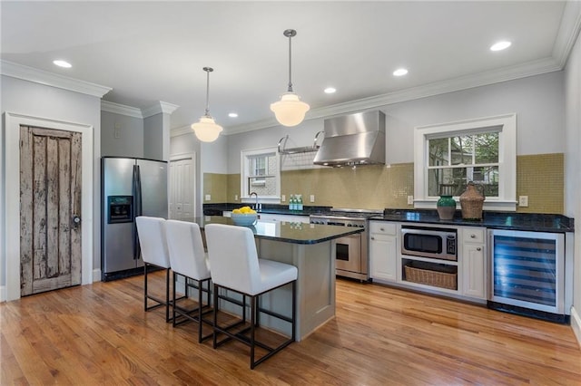 1066 High Point Dr, Atlanta, GA 30306 - kitchen featuring beverage cooler, wall chimney range hood, appliances with stainless steel finishes, dark countertops, and a kitchen bar