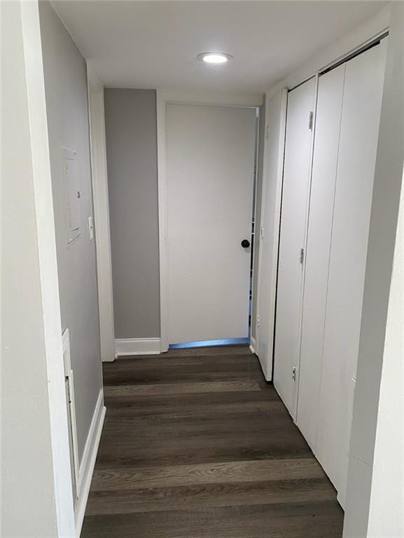 hallway with dark wood-type flooring and baseboards