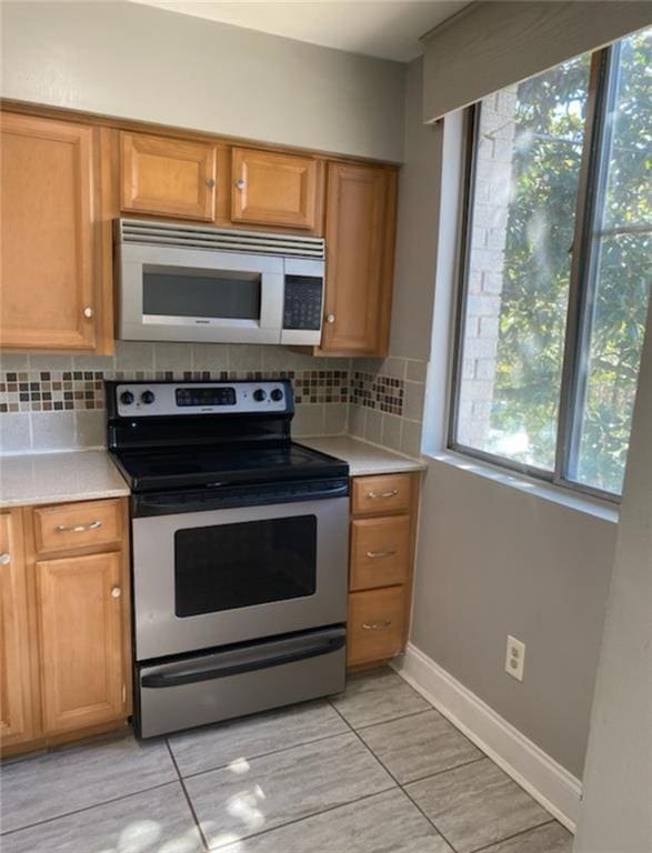 kitchen featuring decorative backsplash, brown cabinets, appliances with stainless steel finishes, and light countertops