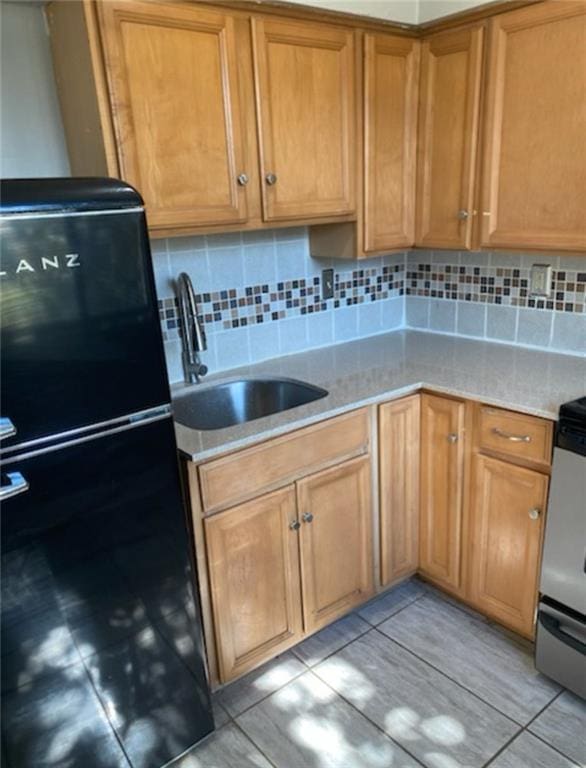 kitchen with a sink, range, tasteful backsplash, and freestanding refrigerator