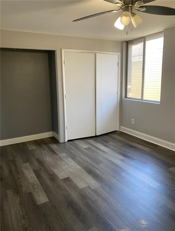 unfurnished bedroom with baseboards, dark wood-style floors, and a ceiling fan