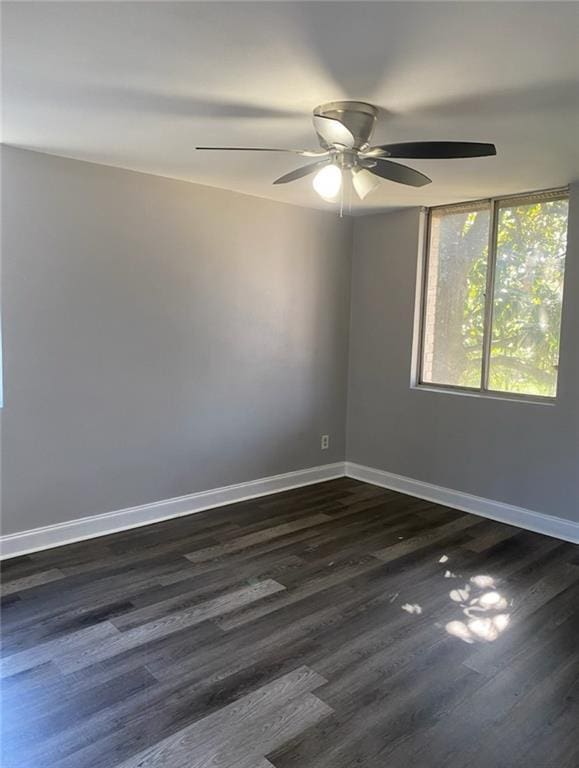 empty room featuring baseboards, dark wood-style floors, and a ceiling fan