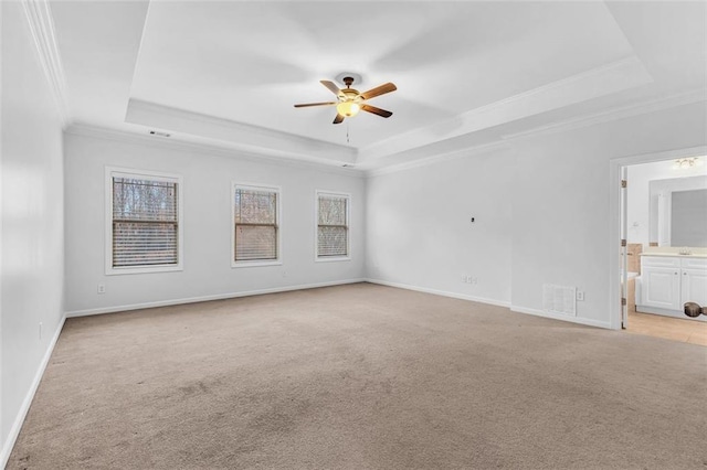 carpeted spare room with a raised ceiling, ornamental molding, and ceiling fan