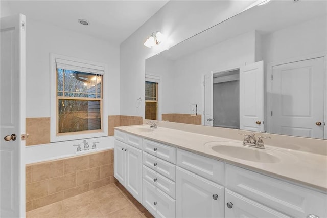 bathroom featuring tile patterned flooring, vanity, and tiled bath