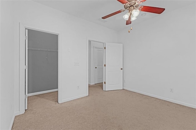 unfurnished bedroom with light carpet, a spacious closet, a closet, and ceiling fan