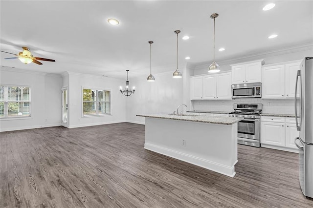 kitchen with white cabinetry, decorative light fixtures, stainless steel appliances, light stone countertops, and a kitchen island with sink