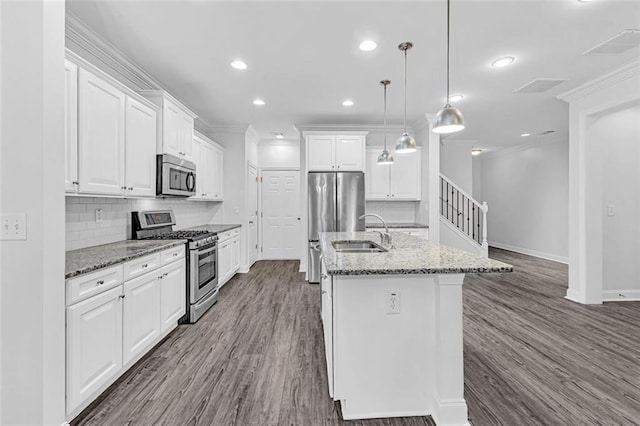 kitchen with sink, decorative light fixtures, stainless steel appliances, a kitchen island with sink, and white cabinets