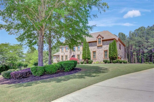 french provincial home featuring stone siding and a front lawn