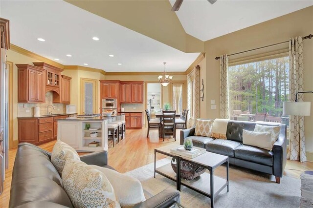 living room with a chandelier, ornamental molding, a ceiling fan, recessed lighting, and light wood-style flooring