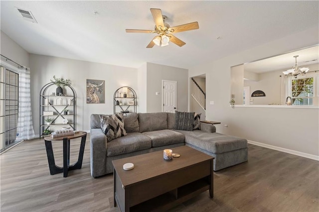 living room with wood finished floors, a chandelier, ceiling fan, stairway, and baseboards