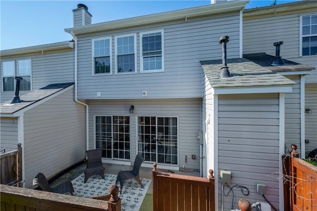 back of property with a chimney, a patio area, and fence