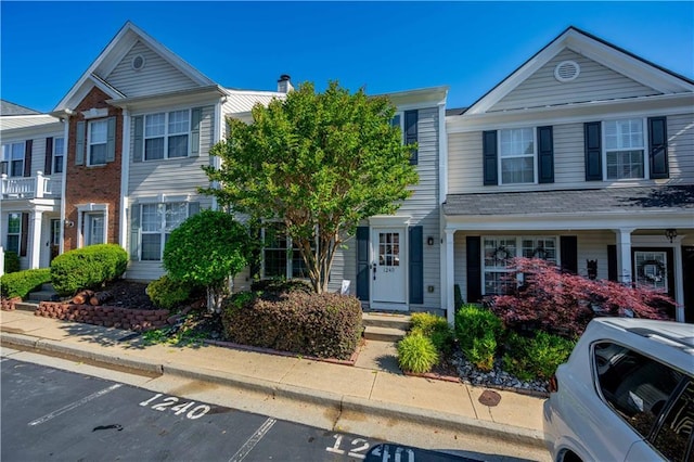 townhome / multi-family property featuring uncovered parking and a chimney