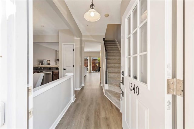 foyer featuring light wood-type flooring, stairway, and baseboards