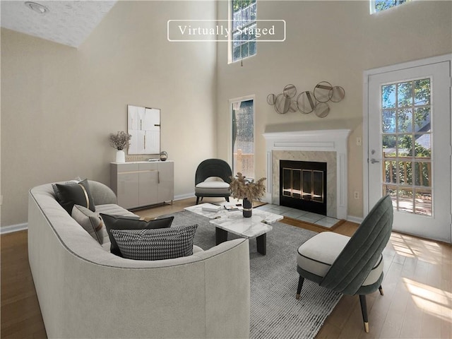 living room featuring a high end fireplace, a towering ceiling, and hardwood / wood-style floors