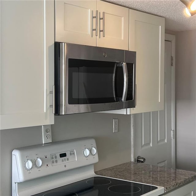 3045 Steeplechase, Alpharetta, GA 30004 - kitchen view of stainless steel microwave, range with electric stovetop, white cabinetry, and light stone counters