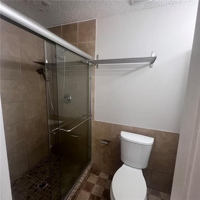 3045 Steeplechase, Alpharetta, GA 30004 - full bathroom featuring tile walls, toilet, a textured ceiling, a shower stall, and wainscoting