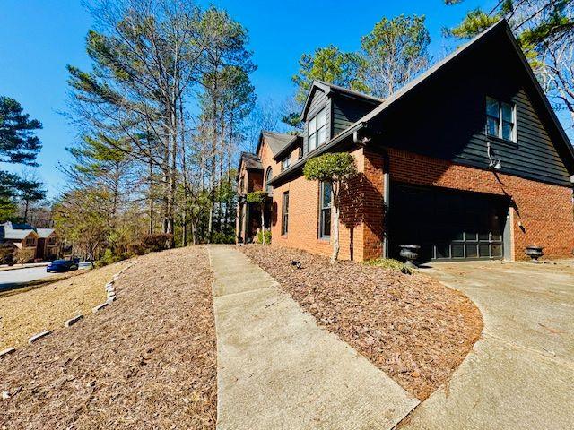 view of side of property with concrete driveway and brick siding