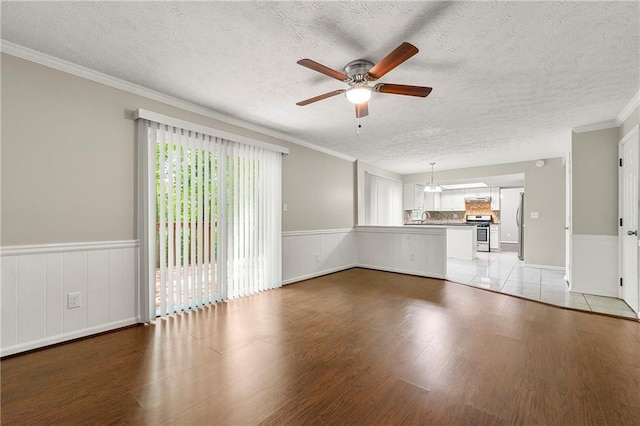 1386 Heritage Glen Dr, Marietta, GA 30068 - unfurnished living room featuring a ceiling fan, light wood-style flooring, a textured ceiling, crown molding, and a wainscoted wall