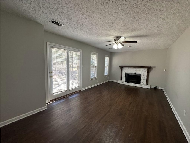 unfurnished living room featuring visible vents, baseboards, dark wood-style floors, a textured ceiling, and a ceiling fan