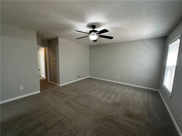 empty room featuring dark colored carpet, baseboards, a textured ceiling, and ceiling fan