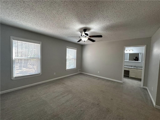 carpeted spare room featuring a ceiling fan, baseboards, and a textured ceiling