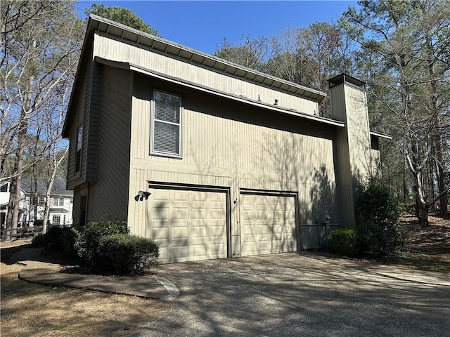 view of home's exterior with a garage, driveway, and a chimney