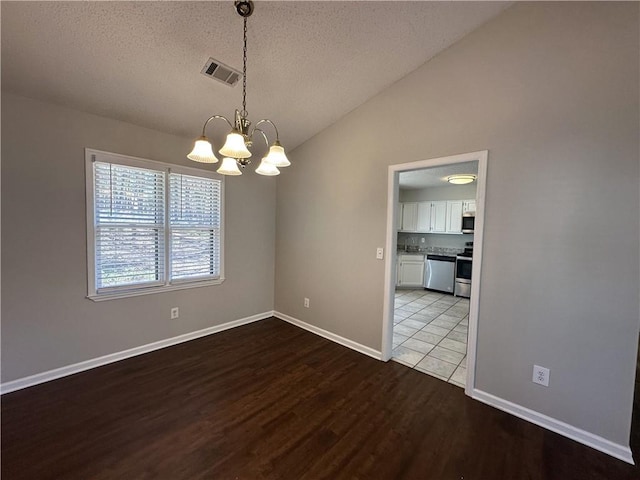 spare room featuring visible vents, a notable chandelier, a textured ceiling, wood finished floors, and vaulted ceiling