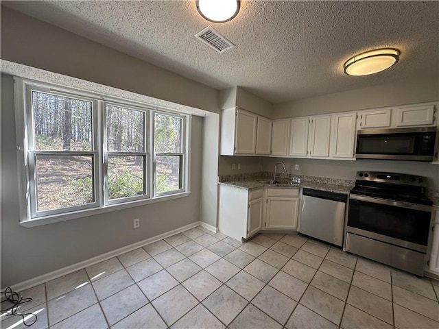 kitchen featuring visible vents, a sink, stainless steel appliances, white cabinets, and light tile patterned floors