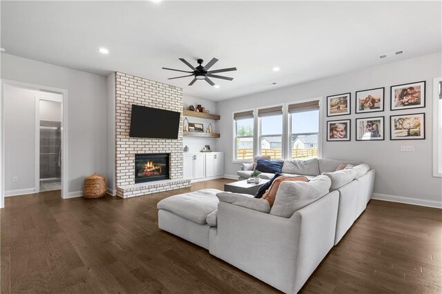 living room featuring ceiling fan, a fireplace, and dark hardwood / wood-style floors