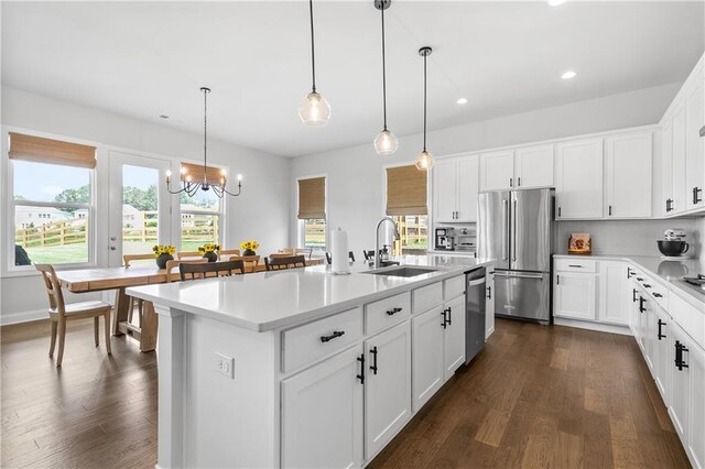 kitchen with a kitchen island with sink, hanging light fixtures, stainless steel appliances, and plenty of natural light