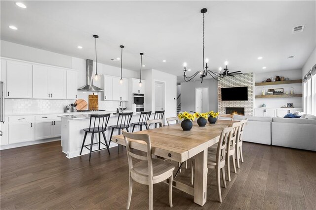 dining room with a fireplace, dark hardwood / wood-style floors, and an inviting chandelier