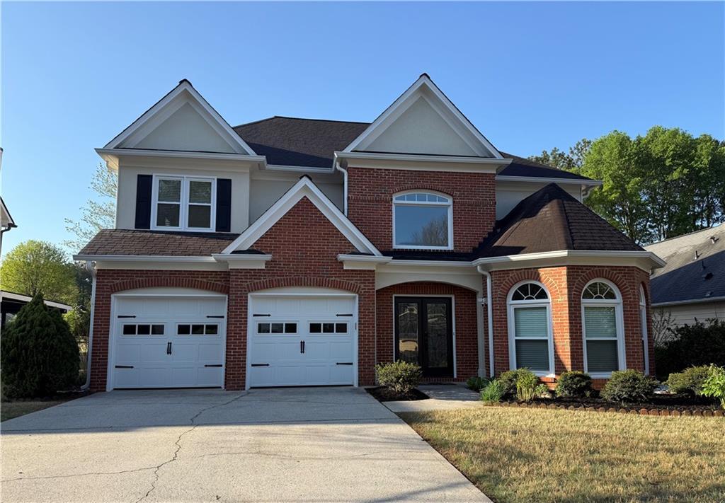 view of front facade with concrete driveway, french doors, a front lawn, brick siding, and a garage