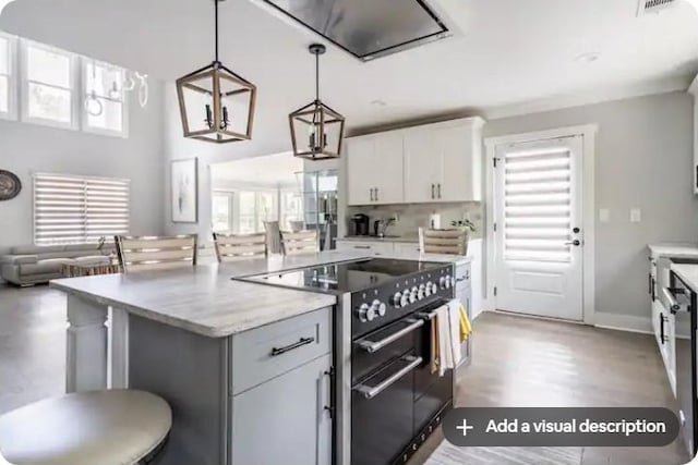 kitchen with high end black range, a kitchen bar, a center island, white cabinets, and pendant lighting