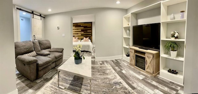 living room with a barn door, built in features, and dark wood-type flooring