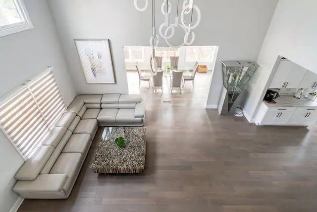 living room featuring a notable chandelier, dark wood-type flooring, and a towering ceiling