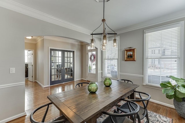 dining room with a chandelier, ornamental molding, light hardwood / wood-style flooring, and french doors