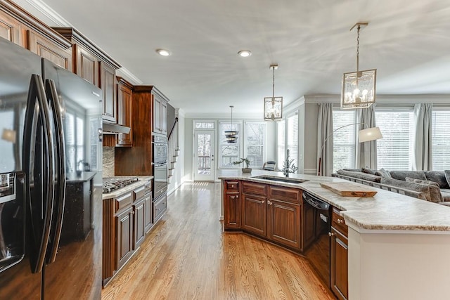 kitchen featuring appliances with stainless steel finishes, crown molding, sink, pendant lighting, and a center island