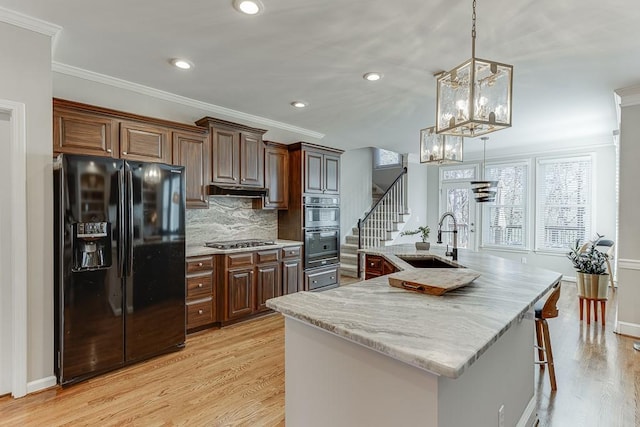 kitchen with a kitchen island with sink, sink, crown molding, and appliances with stainless steel finishes