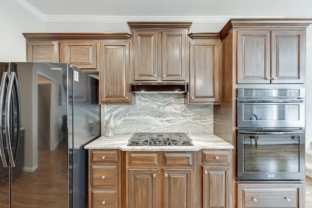 kitchen with tasteful backsplash, black fridge, multiple ovens, stainless steel gas cooktop, and crown molding