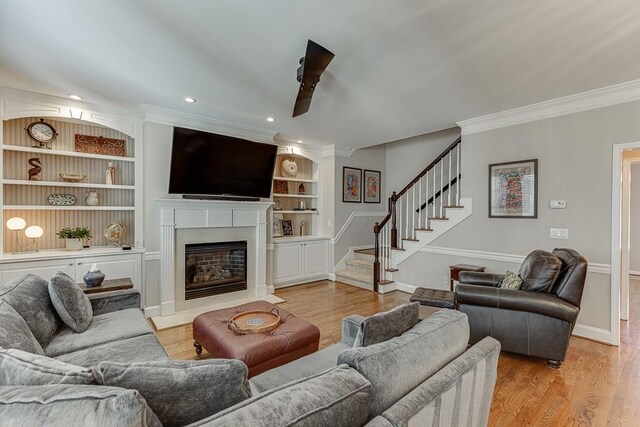 living room featuring crown molding, built in features, and light hardwood / wood-style floors